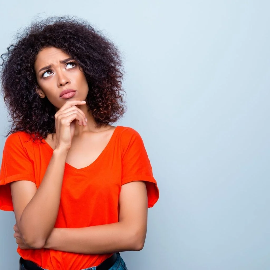 A woman in an orange/red shirt thinking about a puzzling question